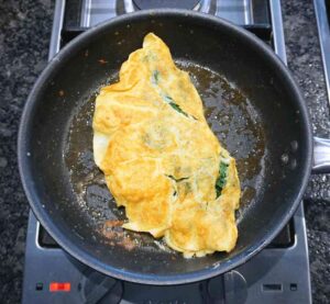 Une omelette délicate et moelleuse est faite en fouettant très bien les œufs, comme si vous alliez faire un gâteau. Feuilles d'épinards fraîches, fromage Cheddar sur le dessus et qui se soucie qu'il ne se plie pas parfaitement