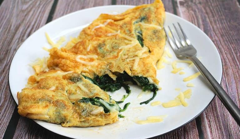 Une omelette délicate et moelleuse est faite en fouettant très bien les œufs, comme si vous alliez faire un gâteau. Feuilles d'épinards fraîches, fromage Cheddar sur le dessus et qui se soucie qu'il ne se plie pas parfaitement